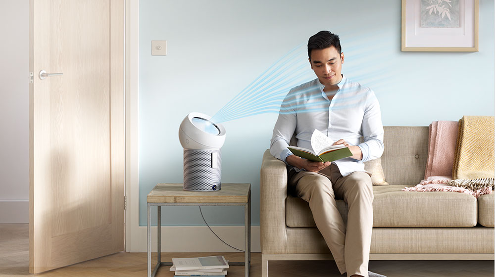 A man reads whilst a Dyson personal purifier fan projects cooling airflow at him